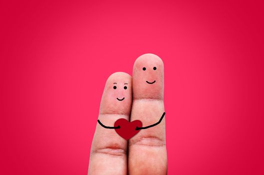 Happy couple in love with painted smiley holding red heart