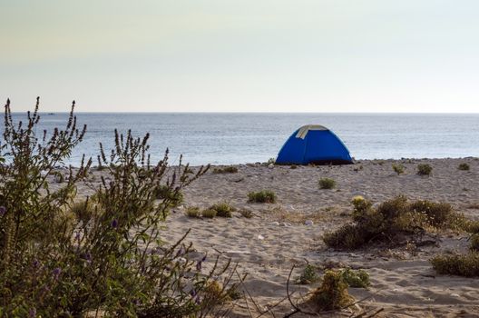 Tent camping on a lonely sandy beach.