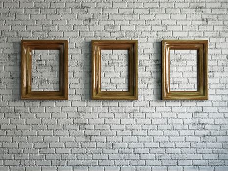 Three empty wooden frames on the brick wall