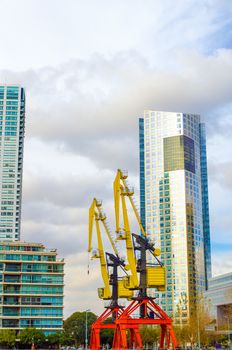 Modern skyscraper in Puerto Madero neighborhood of Buenos Aires with old colorful cranes