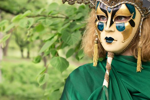 Beautiful woman in carnival mask over foliage background