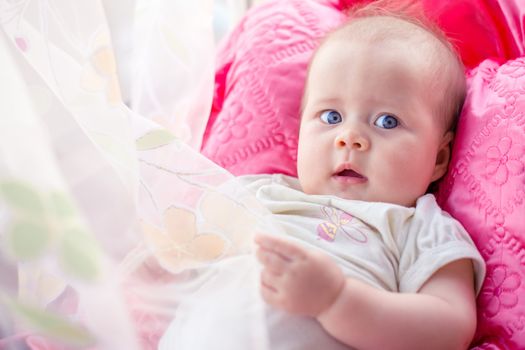 beautiful baby lies quietly on a pink pillow