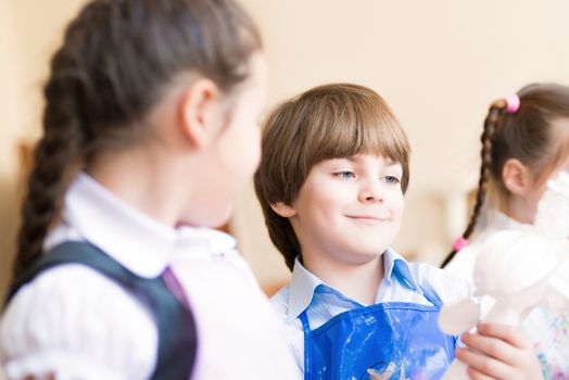 boy draws in the classroom with the other children, the children stand in a row in the table