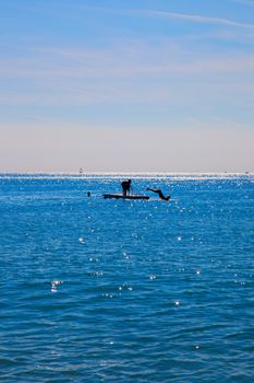 Unrecognizable people diving from a platform in the sea