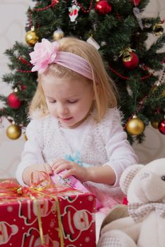 Girl in pink under Christmas tree holding giftbox