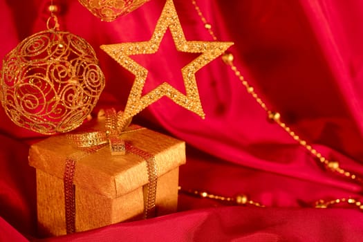 Golden christmas decoration and gift on red fabric background