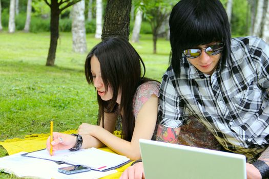 Couple of students studying outdoor with laptop