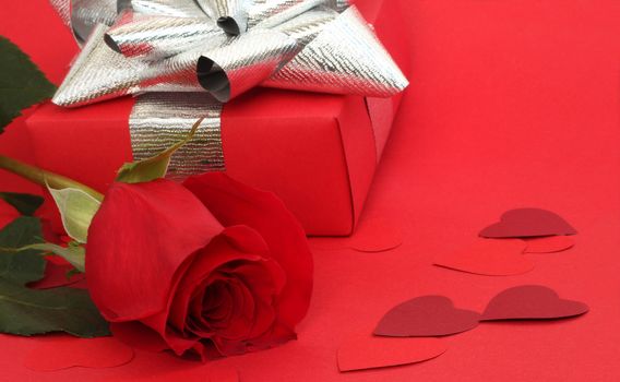 Valentines Day gift in box with rose and small hearts on red background