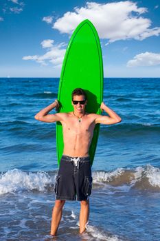 Boy handsome teen surfer holding surfboard in the blue beach