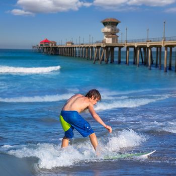 Boy surfer surfing waves on Huntington beach pier California