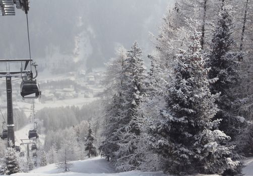 Chair lift between beautiful firs in winter mountains forest