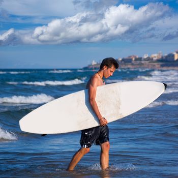 boy handsome surfer holding surfboard coming out from the waves