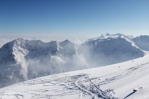 Ski traces on snow in alps under blue sky