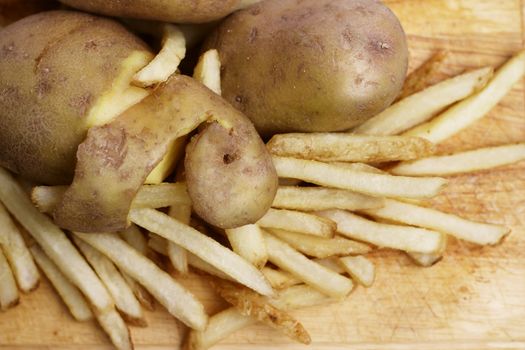 Peeled potato and french fries on wood concept