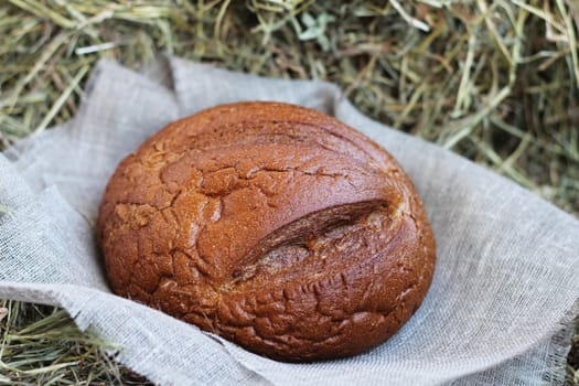 Brown fresh bread and flax textile on hay