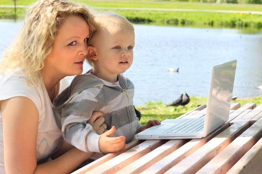 Mother and child with laptop near river
