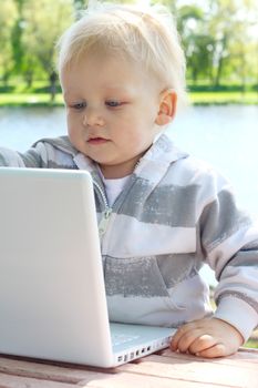 Small child with laptop near river