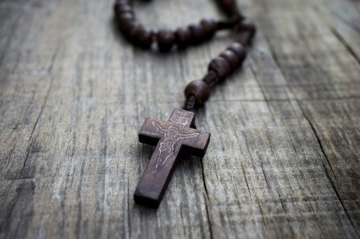 A  rosary with beads on wooden textured background. 