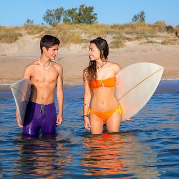 Happy beautiful teenager surfer couple on the beach shore