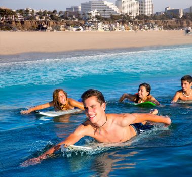 Teenager surfer group boys and girls swimming over the surfboard in santa monica california