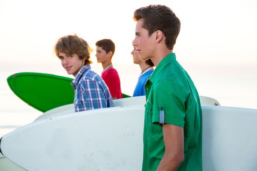 Surfer teenager boys group walking at beach shore on sunshine or sunset