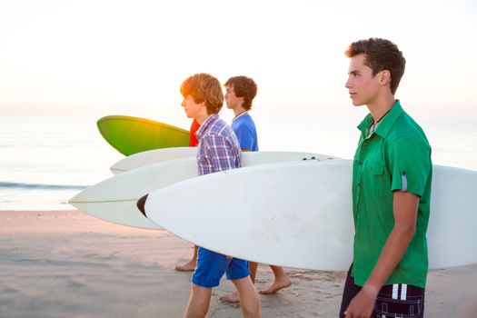 Surfer teen boys group walking at beach shore on sunshine or sunset