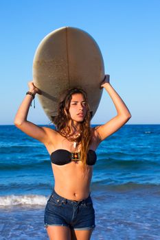 Brunette surfer teen girl holding surfboard in blue beach
