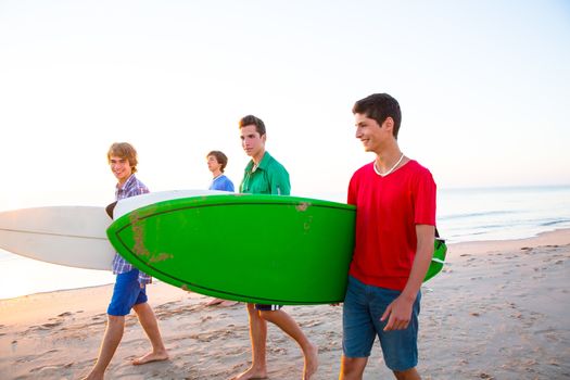 Surfer teen boys group walking at beach shore on sunshine or sunset