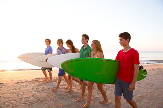 Surfer teen boys girls group walking on beach at sunshine sunset