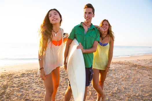 Surfer girls with teen boy walking on beach shore high key