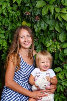 Mother holds daughter on hands on a background of city park