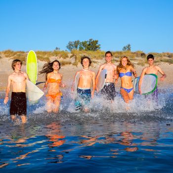 surfer teenagers boys and girls group running happy to the beach splashing water