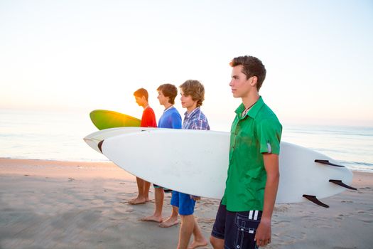 Surfer teenager boys group walking at beach shore on sunshine or sunset