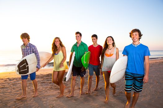 Surfer teen boys girls group walking on beach at sunshine sunset
