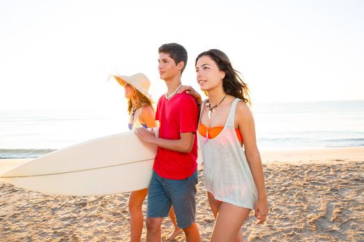 Surfer girls with teen boy walking on beach shore high key