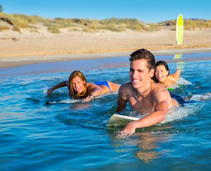 Teenager surfer group boys and girls swimming over the surfboard