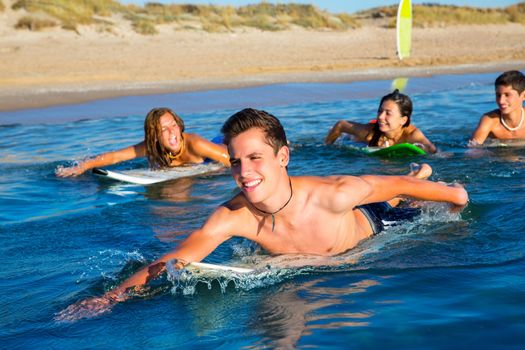 Teenager surfer group boys and girls swimming over the surfboard