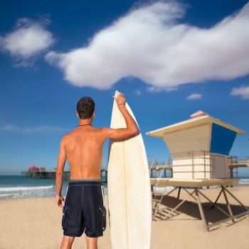 Boy surfer back rear view holding surfboard on Huntinton beach lifeguard house