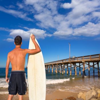Boy surfer back rear view holding surfboard on Newport pier beach California