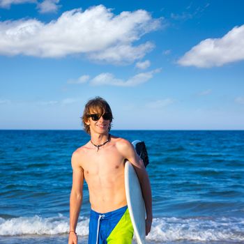 Boy teen surfer happy holing surfboard on the beach shore