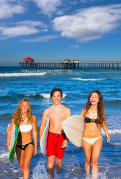 boys and girls teen surfers coming out from the Huntington beach California