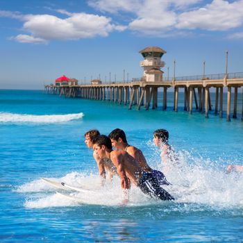 Teenager surfers surfing running jumping on surfboards at Huntinton beach pier California