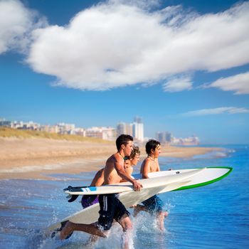 Teenager surfers surfing running jumping on surfboards at El Perello Cullera beach Spain