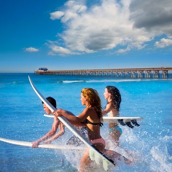 Teenager surfers surfing running jumping on surfboards at Newport pier beach California