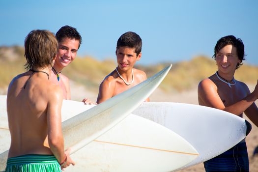 Surfer teen boys talking on beach shore holding surfboards