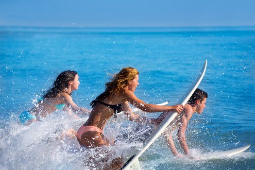 Boys and girls teen surfers running jumping on surfboards at the beach