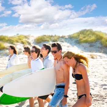 Surfer teen boys and girls group walking on beach sand