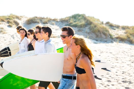 Surfer teen boys and girls group walking on beach sand