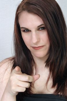 A close-up of a lovely young brunette pointing her index finger as if she's warning or scolding you.