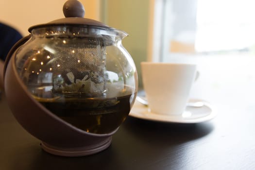 brown hot tea pot on table with white cup